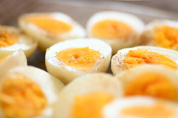 A closeup photo of boiled and halved chicken eggs sprinkled with salt and pepper, showcasing their texture and simplicity