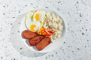 A top down view of a pork luncheon meat breakfast entree.