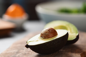 Ripe avocado sliced in halves on olive wood board with copy space