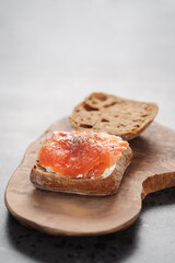 rye ciabatta sandwich with smoked salmon and cream cheese on olive board