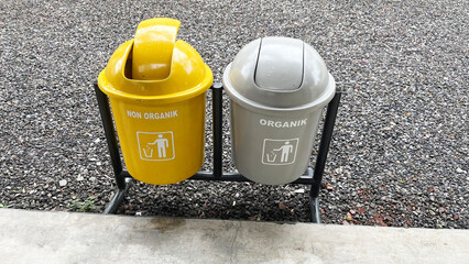 Two coloured recyclable bins in public area. Yellow and grey trash bins for organic and non-organic...