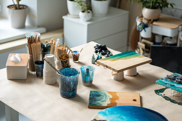 Creative artist studio with epoxy art of water wave patterns. Brushes paints and cups, wooden board with drying artwork. Inspiration, essence of artistry, creative occupation, hobby and job, DIY