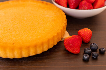 Sponge cake on the table. The process of making strawberry pie. Strawberries
