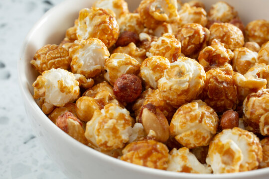 A closeup view of a bowl of caramel coated popcorn snack.