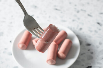 A closeup view of a fork picking up a Vienna sausage.
