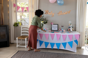 Decorating baby shower table, woman arranging cupcakes and colorful banners, at home