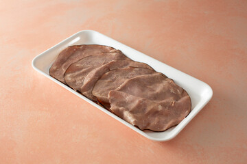 A view of a stack of roast beef slices, on a tray.