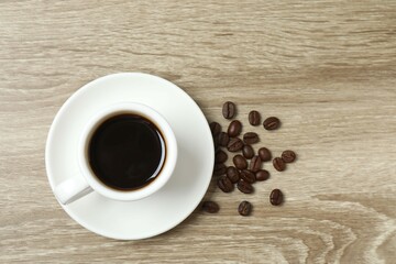 Cup of coffee and coffee beans on wooden background
