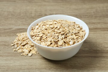 Composition with oatmeal flakes on wooden background. Cooking breakfast