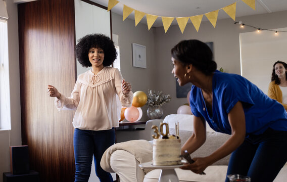 diverse female friends celebrating birthday at home with cake and decorations
