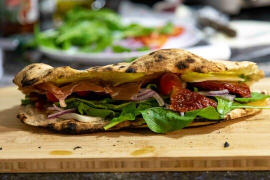 Traditional Italian Neapolitan panuozzo prepared with artisanal pizza dough, arugula and sun-dried tomatoes