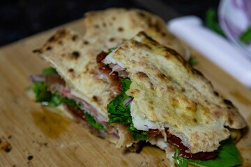 Traditional Italian Neapolitan panuozzo prepared with artisanal pizza dough, arugula and sun-dried tomatoes