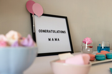 Celebration setup with congratulatory sign, colorful macarons, and festive drinks, at home