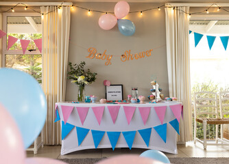 Baby shower decorations with pink and blue balloons and festive table setup, at home