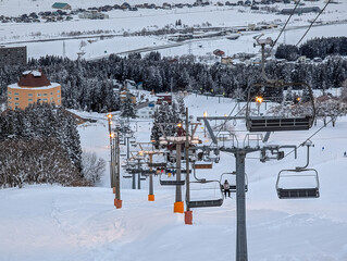 Ski lift transporting skiers up a slope at dusk