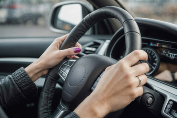 The woman's hands on the steering wheel of the car close-up