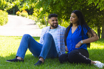 Couple relaxing on grass in park, enjoying sunny day and each other's company