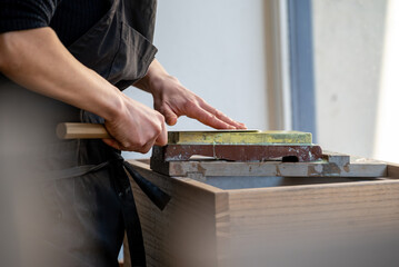 Un artisan professionnel nettoyant et affûtant des couteaux japonais, illustrant son expertise dans le métier de coutellerie traditionnelle.