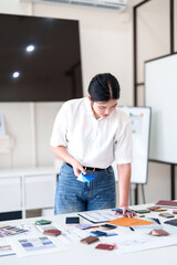 Young architect selecting materials and color swatches while standing at modern interior design...