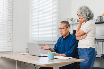 Obraz premium Elderly couple discussing pension savings while using laptop in bright home office, expressing concern and focus.