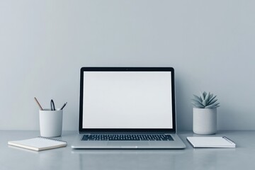 white desktop with open laptop showing blank screen surrounded by minimalistic office items like coffee cup pen and