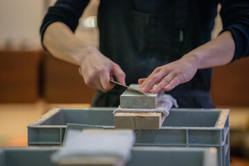 Un artisan professionnel nettoyant et affûtant des couteaux japonais, illustrant son expertise dans le métier de coutellerie traditionnelle.