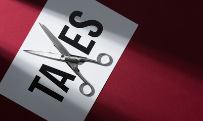 TAXES text on a sheet and scissors: tax cut concept