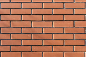 Fototapeta premium Red brick wall with a classic horizontal pattern. The texture and symmetry make it a perfect background for design, construction, and urban themes, durability, strength, and industrial aesthetics.