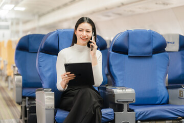 Businesswoman on Airplane: A professional woman, engrossed in a phone call, deftly manages her...