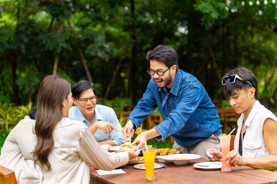 Group of Happy Asian millennial generation people friends enjoy and fun celebration reunion meeting at outdoor dinner party with food and drink together in the garden at restaurant on holiday vacation