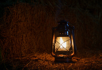 antique kerosene lamp with lights on a haystack in a barn at night