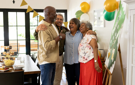 diverse senior friends celebrating together at home, smiling and embracing joyfully