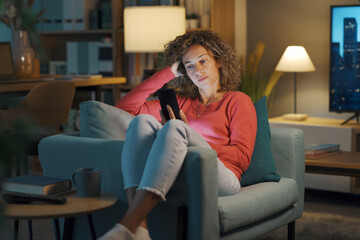 Obraz premium Young woman chatting with her smartphone at home