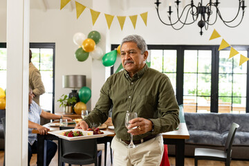 Man carrying food and drink at home party, looking cheerful and welcoming