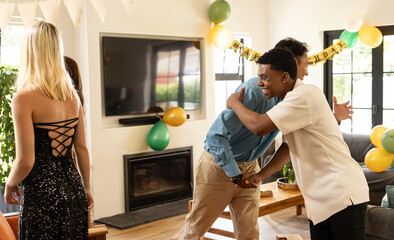 man greeting diverse friends at home birthday party, smiling warmly