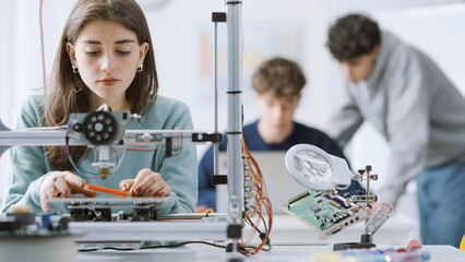 Female student using a 3D printer in the lab