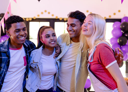 Diverse friends celebrating together at party, smiling and enjoying party decorations, at home