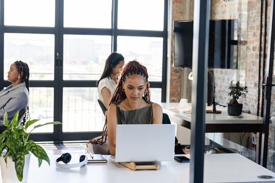 woman working on laptop in modern office, focused and productive