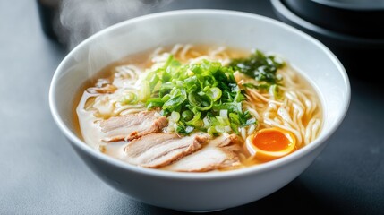 Delicious steaming ramen bowl with sliced pork, green onions, egg, and seaweed on a dark table