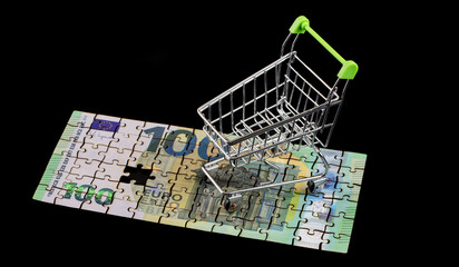 A 100 euro note made from puzzle pieces and an empty supermarket shopping cart