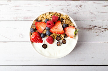 Muesli with organic berries and nuts. Oat muesli with raspberry, blueberry, strawberries, almond, cashew, banana. Healthy food, top view