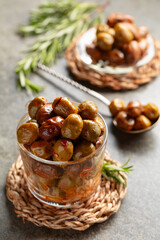 Spicy olives in a glass bowl on a stone table.