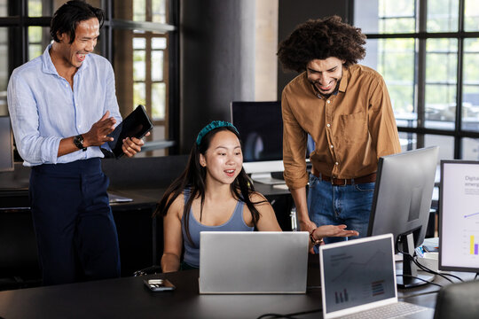 Diverse business team collaborating on project with laptops and digital charts, at office