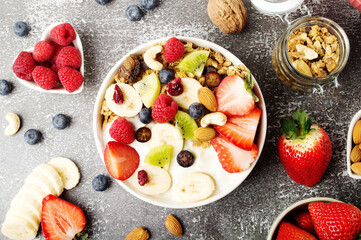 Muesli with organic berries and nuts. Oat muesli with raspberry, blueberry, strawberries, kiwi, almond, cashew, banana. Healthy food, top view