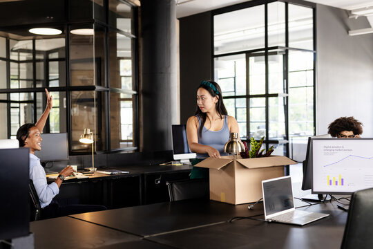 Diverse colleagues in modern office unpacking boxes and setting up workstations