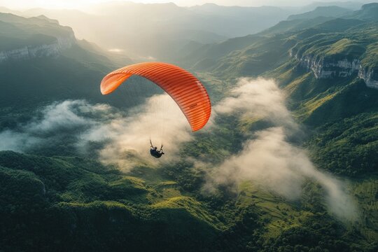 Paraglider soars above misty mountain valley at sunrise