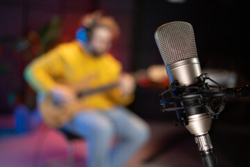 A focused male musician fine-tunes a bass guitar against the backdrop of a digital sound editing...
