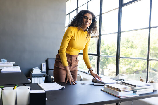Organizing documents on desk in modern office, confident businesswoman working