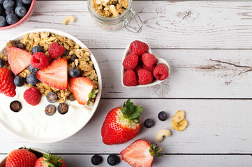 Muesli with organic berries and nuts. Oat muesli with raspberry, blueberry, strawberries, almond, cashew, banana. Healthy food, top view