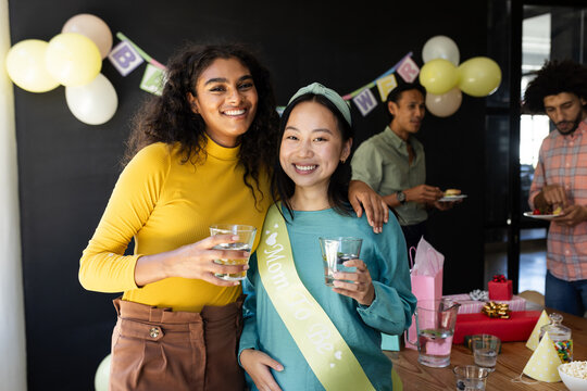 Celebrating baby shower, diverse friends enjoying drinks and smiling at party, at office